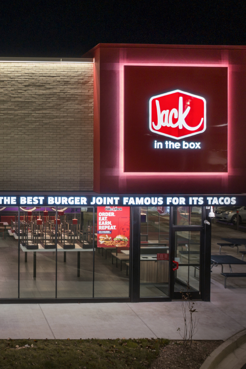 Illuminated Jack in the Box branding panel above the walk-up entry at night