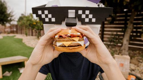 Jack Box in sunglasses eating Jack in the Box Hmaburger