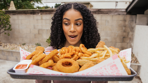 A person looking at a tray of Jack in the Box fries and onion rings