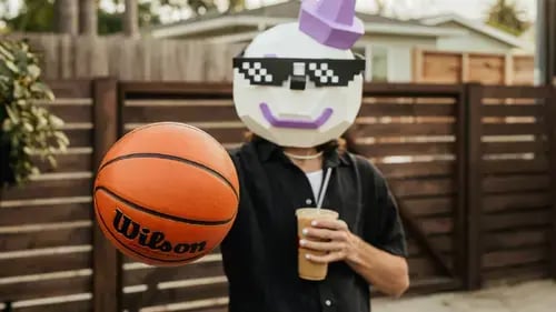 Jack Box palming a basketball with a coffee in his hand.