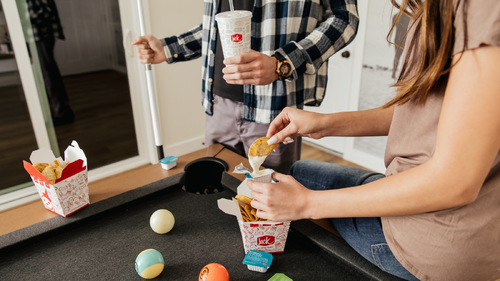 Friends eating Jack in the Box Tiny Tacos while playing pool.